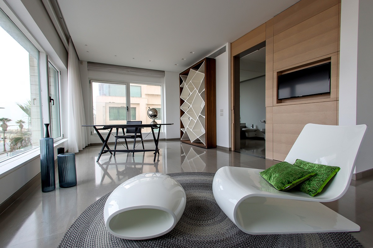 A modern living room with a white chair and a white rug.