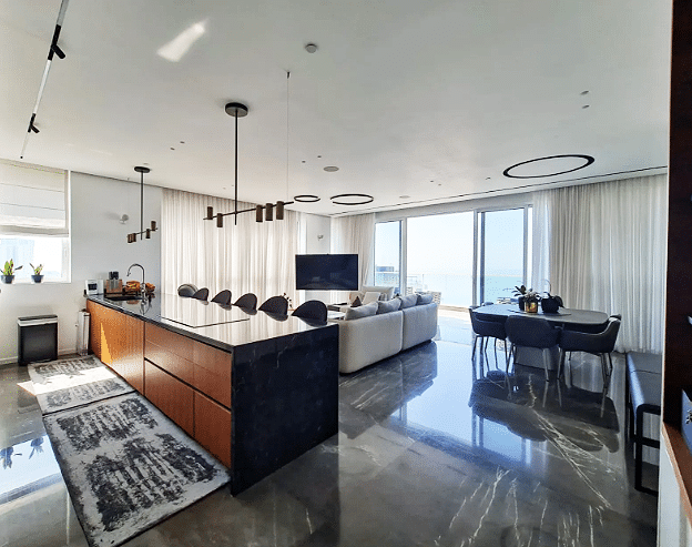A modern kitchen and living room with a view of the ocean.