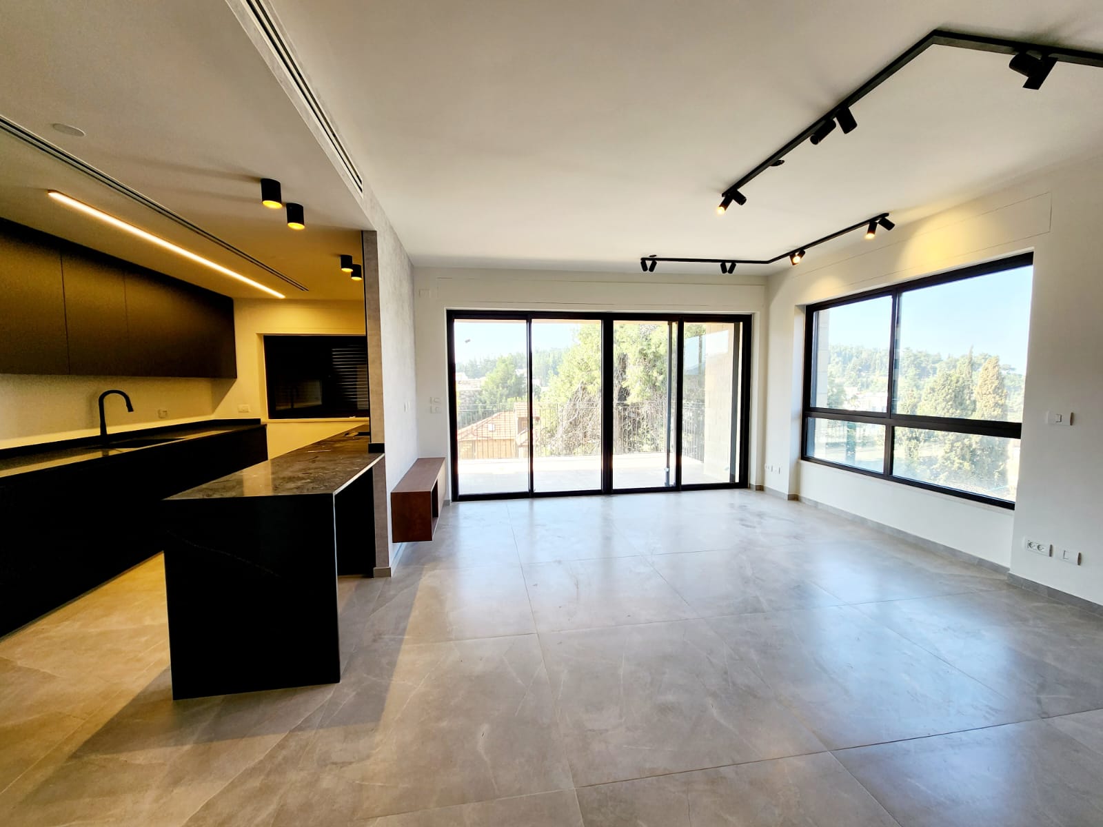 A modern apartment with a large kitchen and large windows.