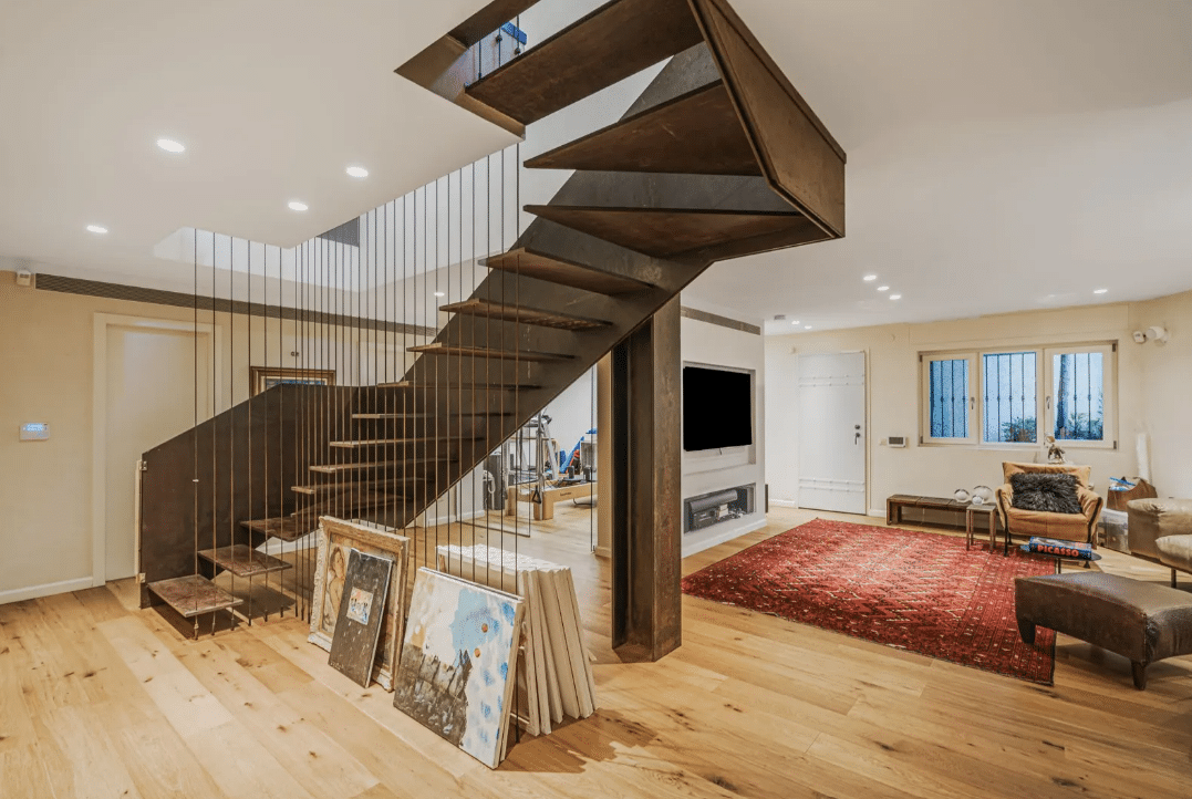 A modern living room with wooden floors and a spiral staircase.