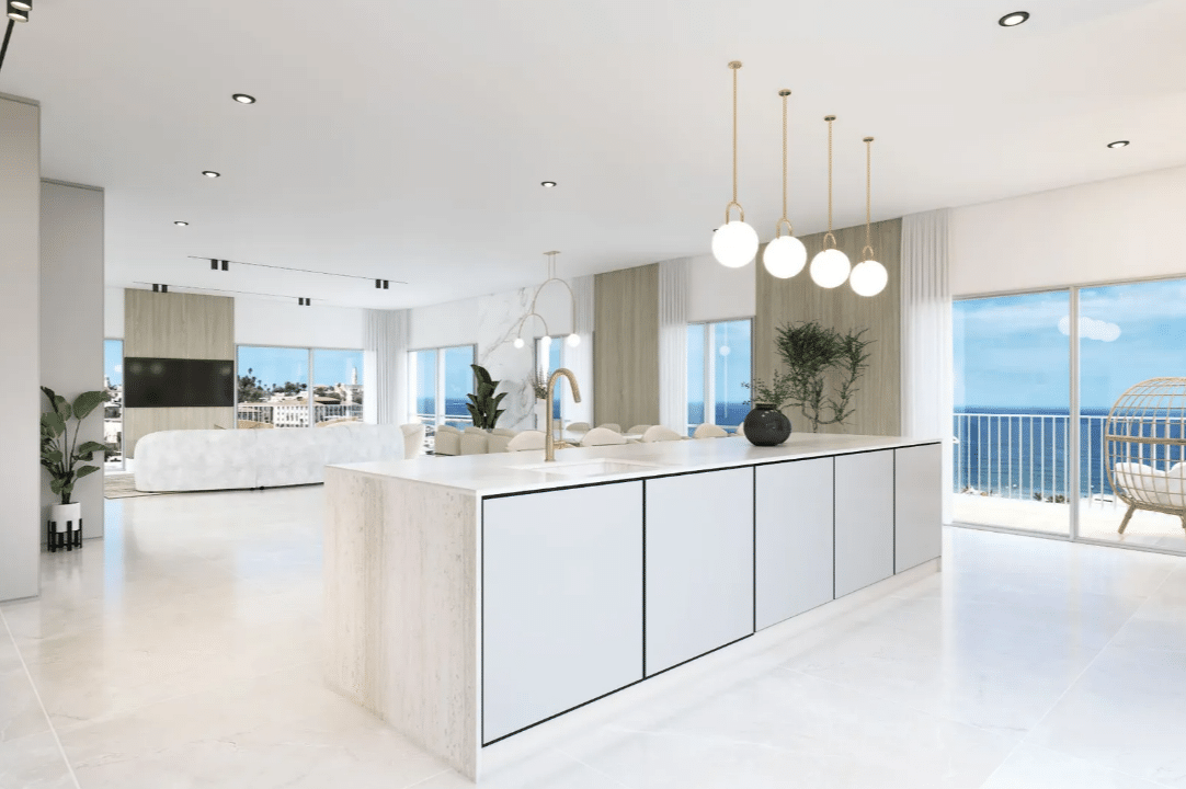 A white kitchen with a view of the ocean.