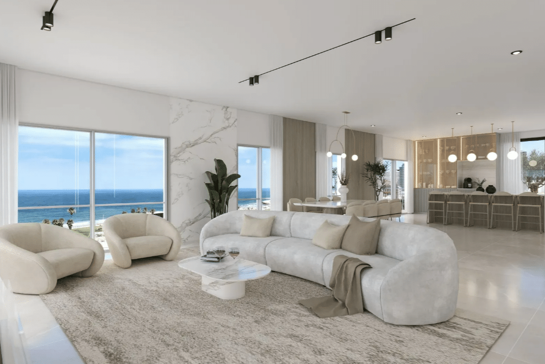 A white living room with a view of the ocean.