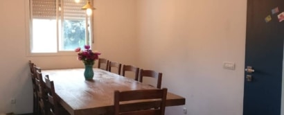 A dining room with white walls a wooden table and chairs.