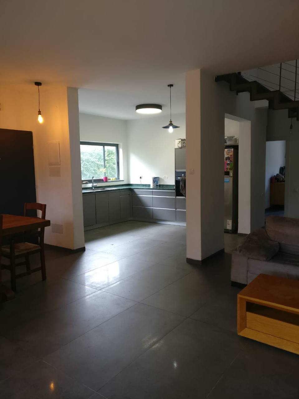 A living room with a kitchen and stairs.